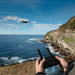 Aeroo Pro Drone flying in the sky with remote controller and screen in foreground